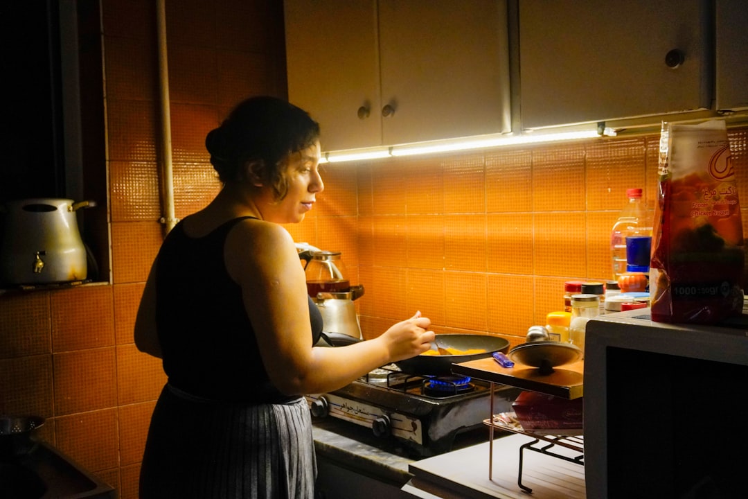 A woman cooks food in a small kitchen.
