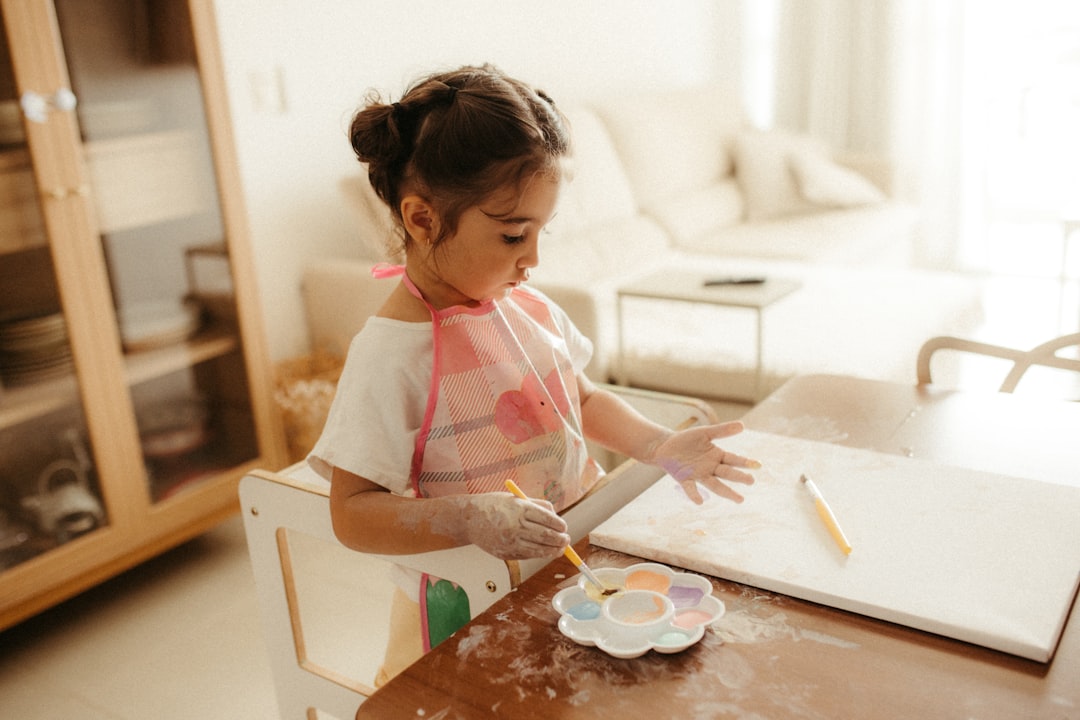Young girl painting at a table with watercolors.