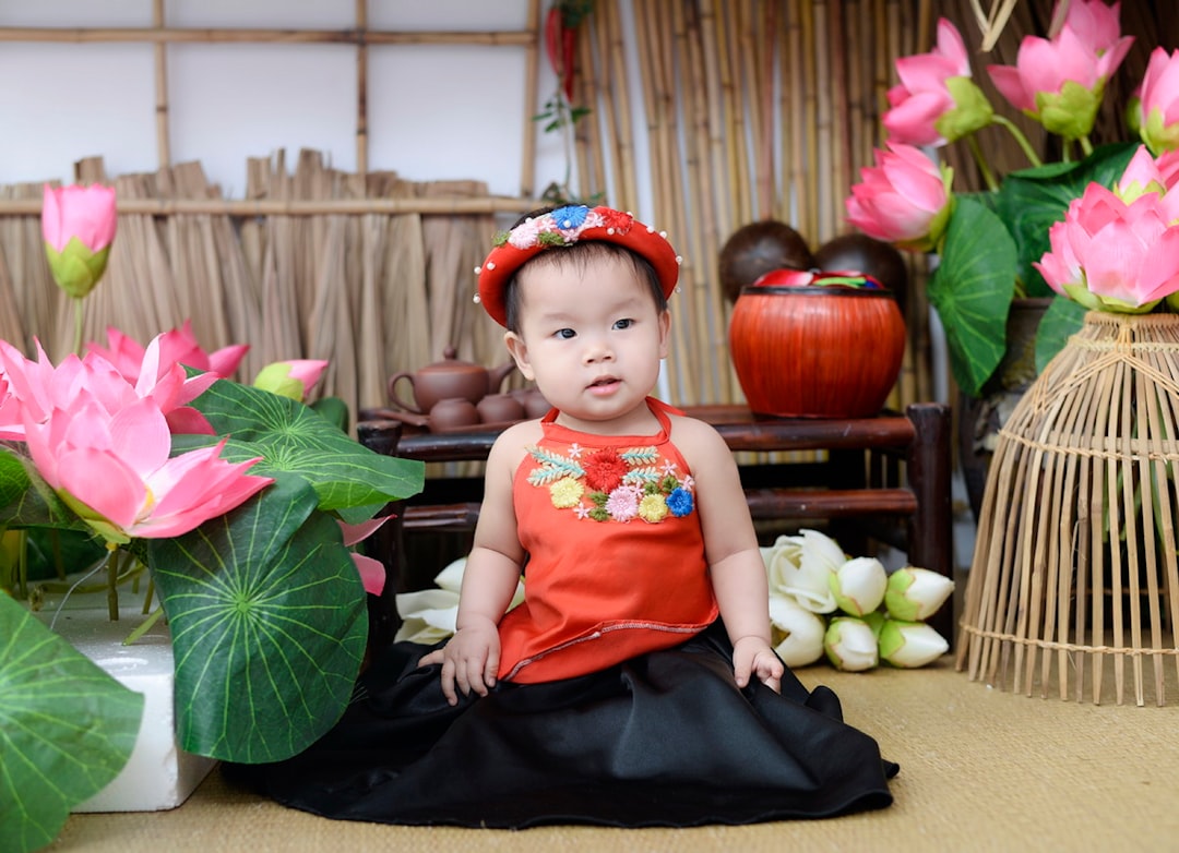 a little girl sitting on the ground next to flowers