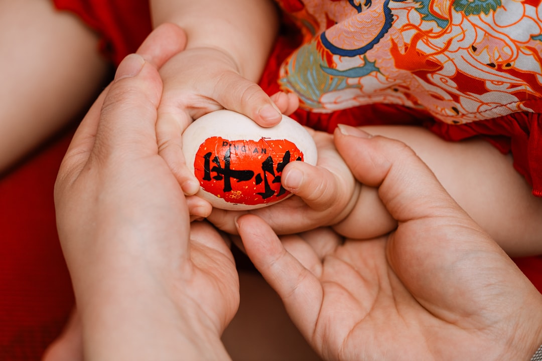A baby holds a decorated egg in its tiny hands.