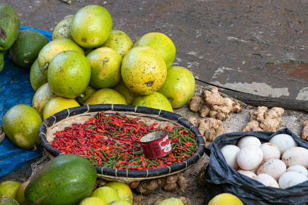 A pile of citrus fruits, red chili peppers, ginger, and eggs at a market