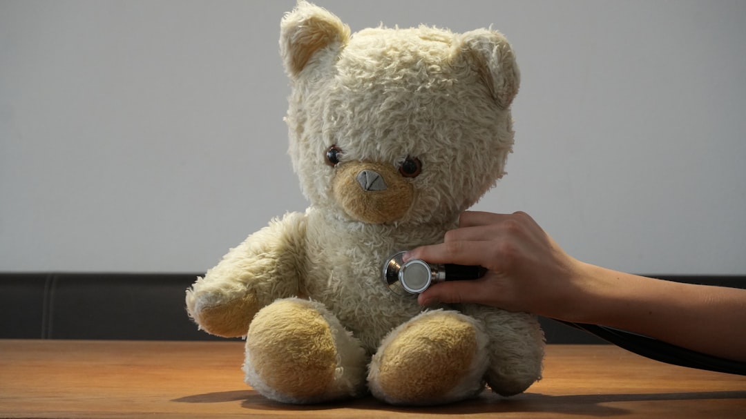 Hand using stethoscope on teddy bear's chest.