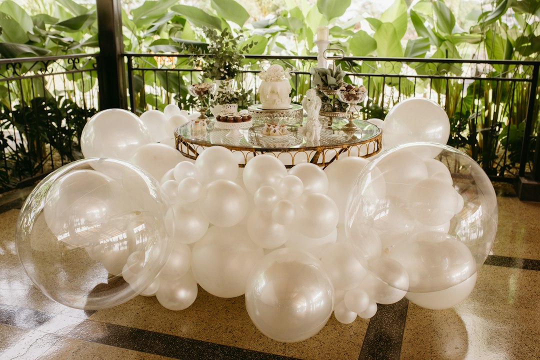 A dessert table decorated with white balloons and clear bubbles