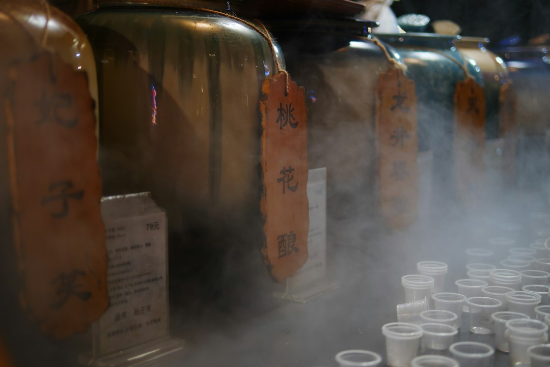 Large ceramic jars with wooden labels and small plastic cups in swirling white mist