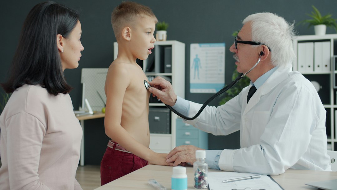 Doctor examines a young boy's chest with stethoscope