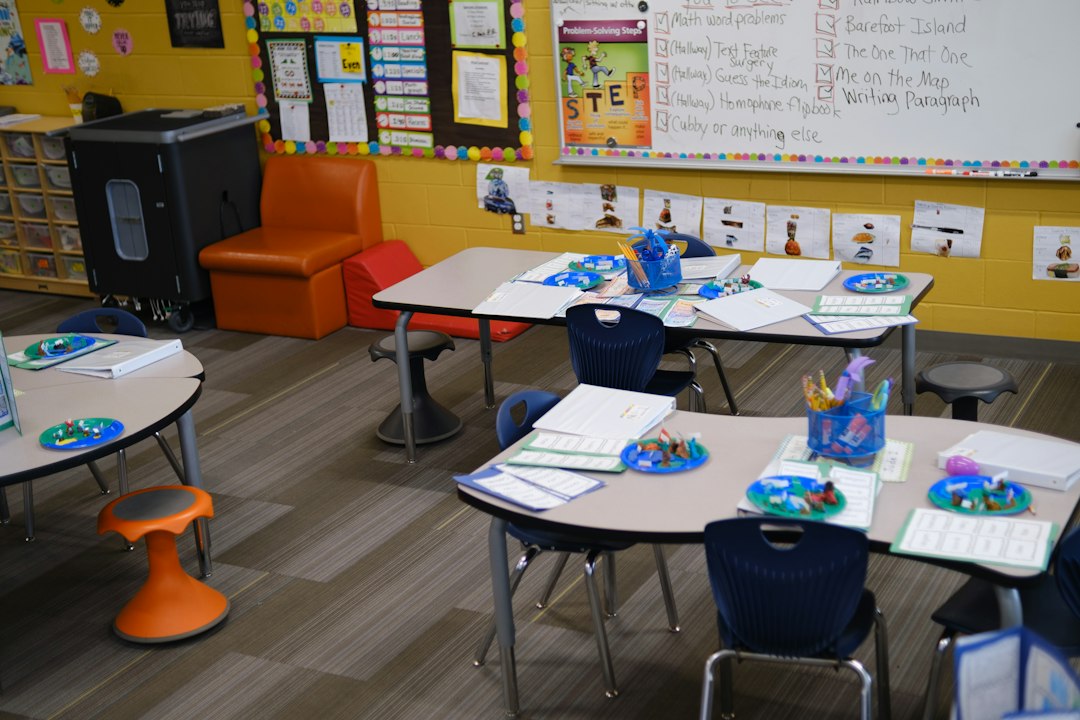Tables with blue chairs and student materials in a colorful elementary school classroom