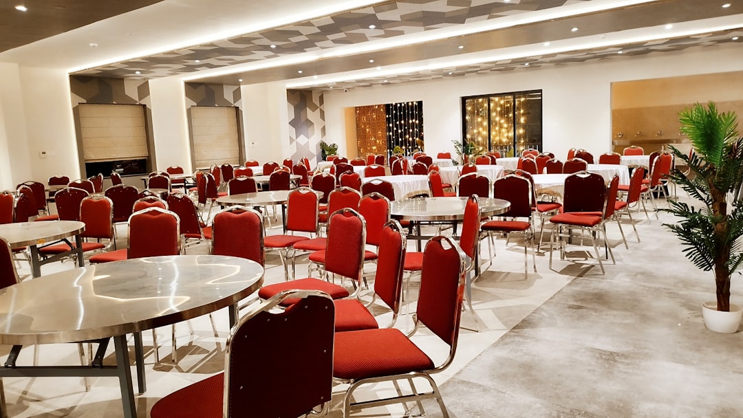 Empty banquet hall with red chairs and round tables.