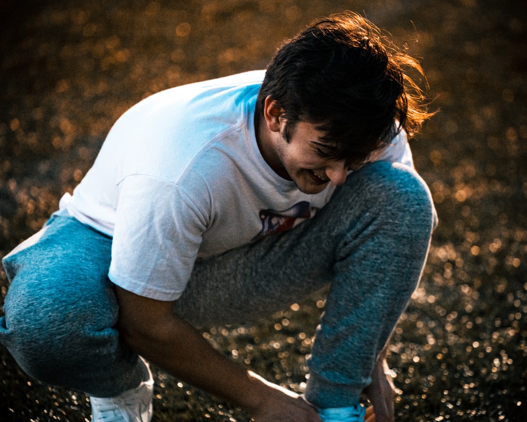 a man kneeling down in the grass with his hands on his knees