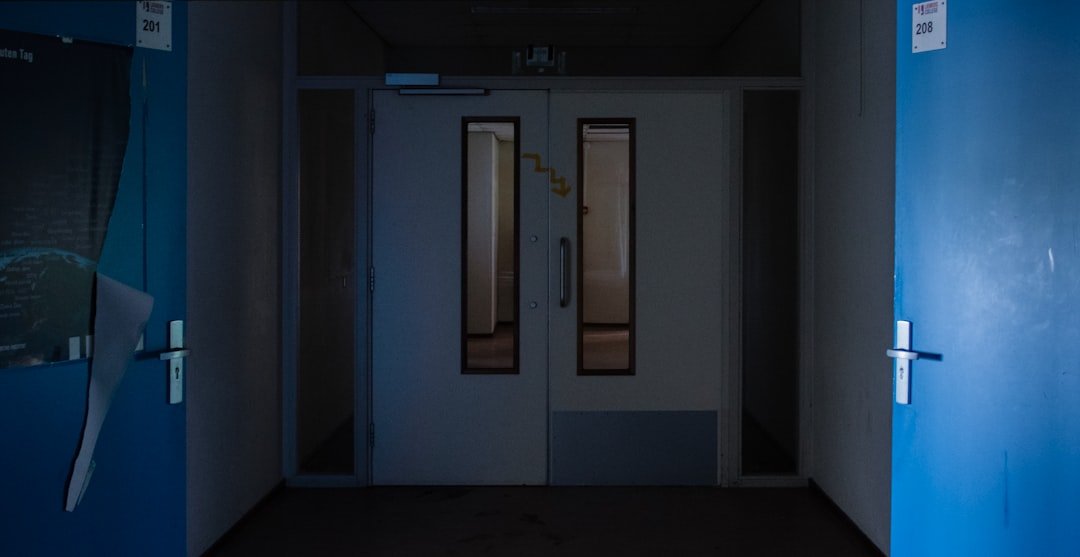 a dark hallway with a blue door and white walls