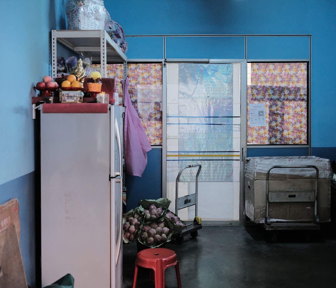 white top mount refrigerator beside white plastic container