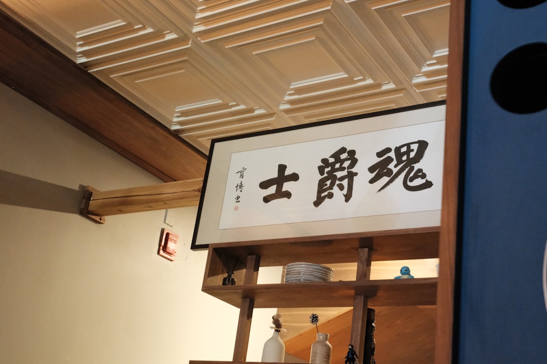 Calligraphy scroll with japanese characters hangs on wall.