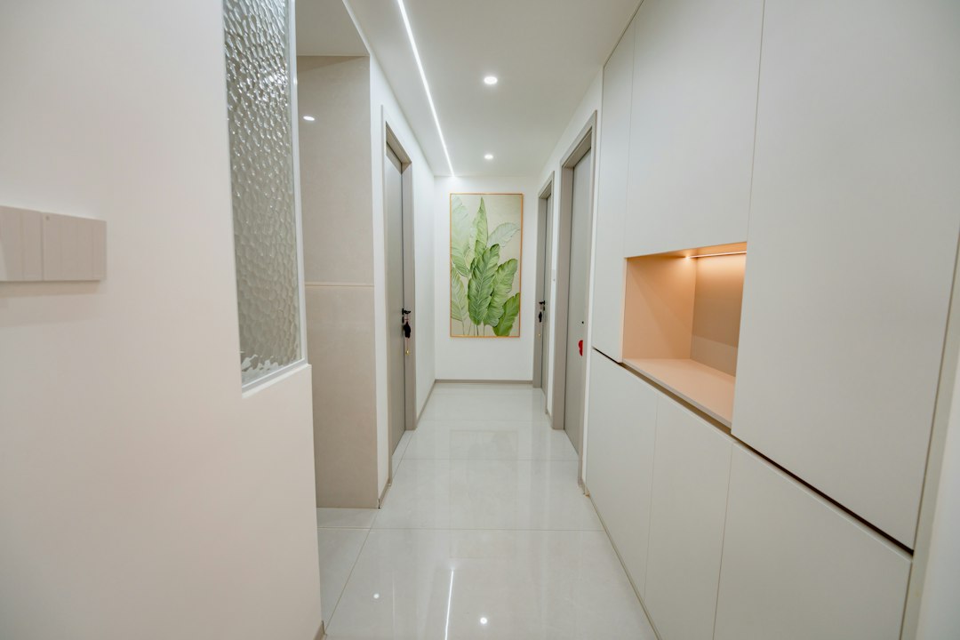 A bright hallway with white walls, tiled floors, and a botanical painting