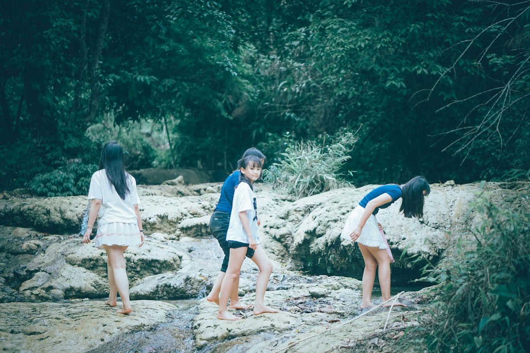 Three girls walk by a rocky stream