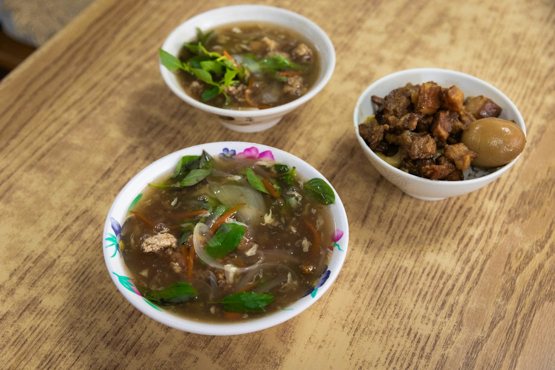A wooden table topped with three bowls of food
