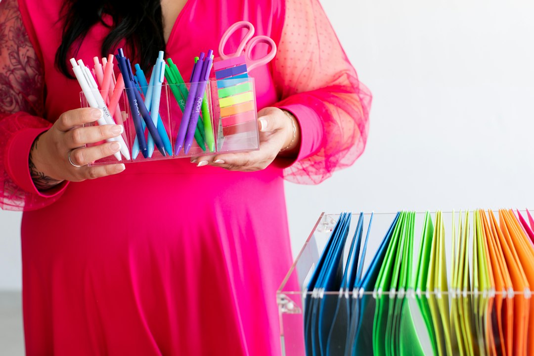 Woman in pink dress holding colorful pens and scissors