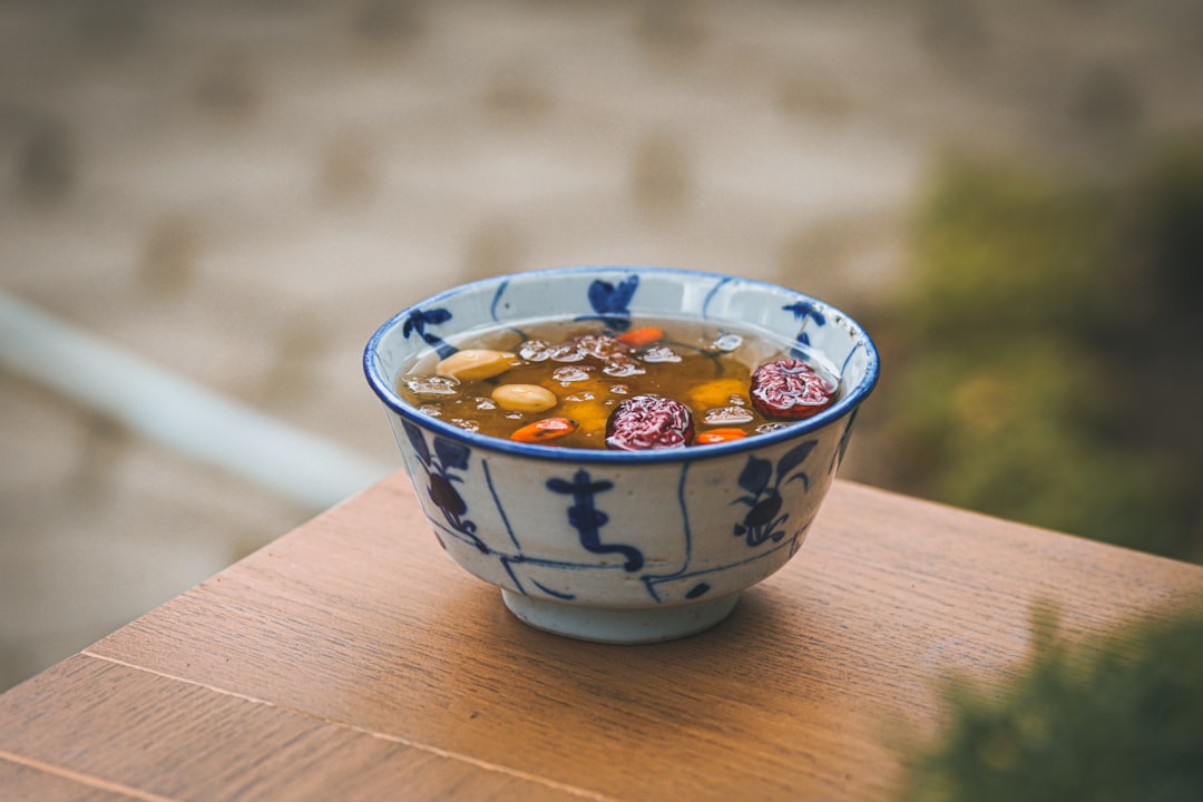 white and blue ceramic bowl on brown wooden table