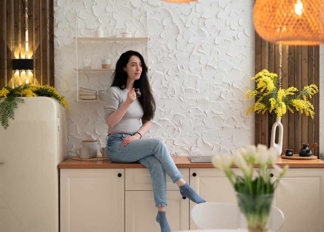 a woman sitting on top of a counter next to a vase