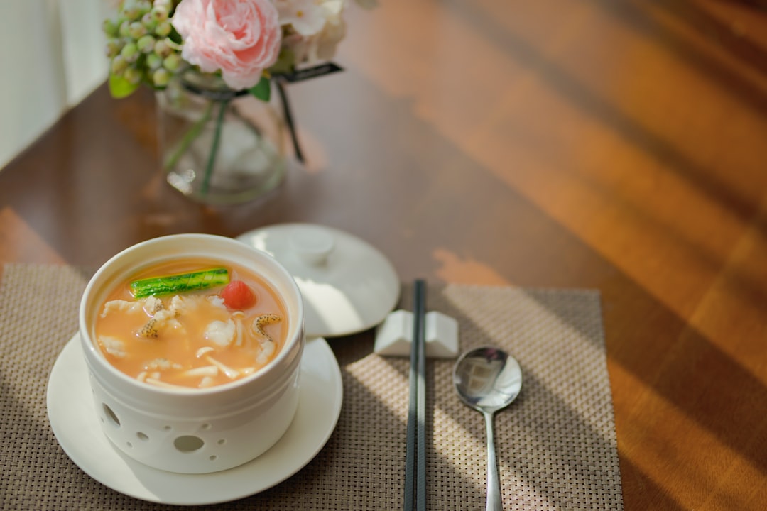 white ceramic bowl with soup and stainless steel spoon on table