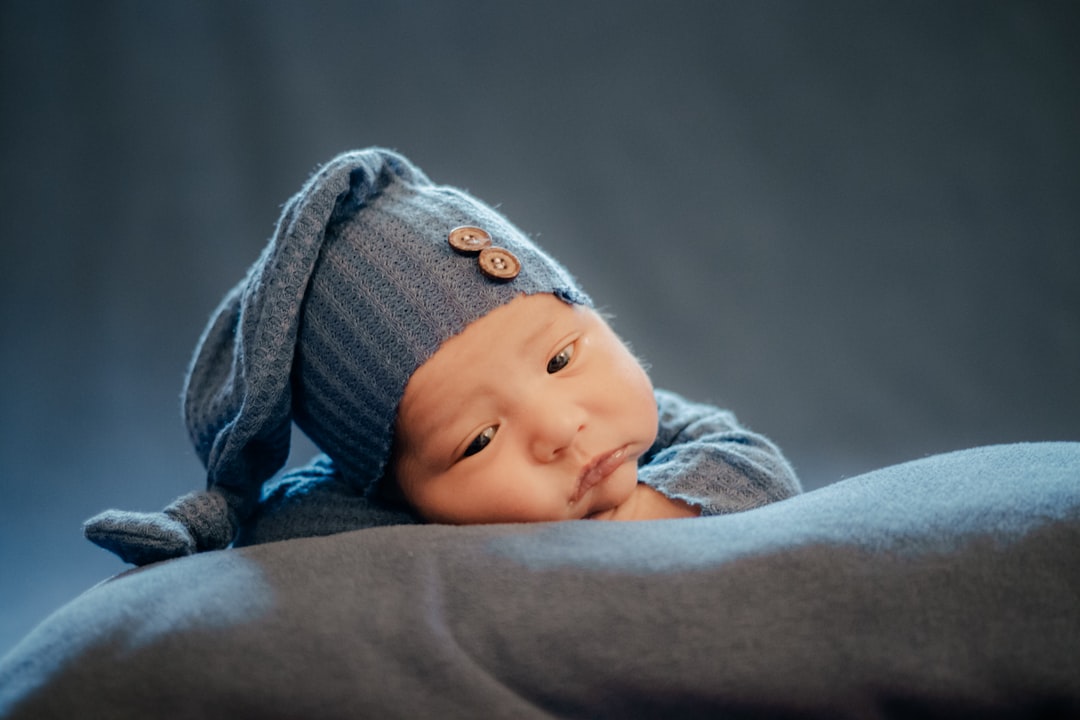 a baby doll wearing a blue hat on top of a bed