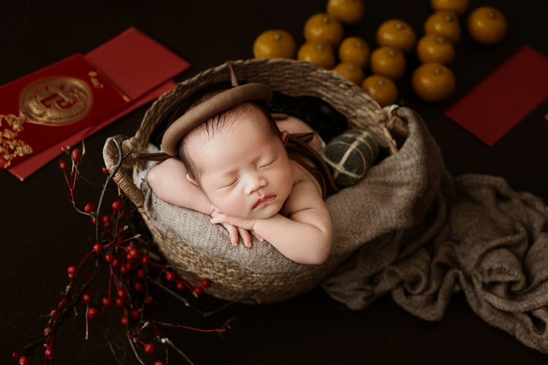 A baby sleeping in a basket next to some oranges