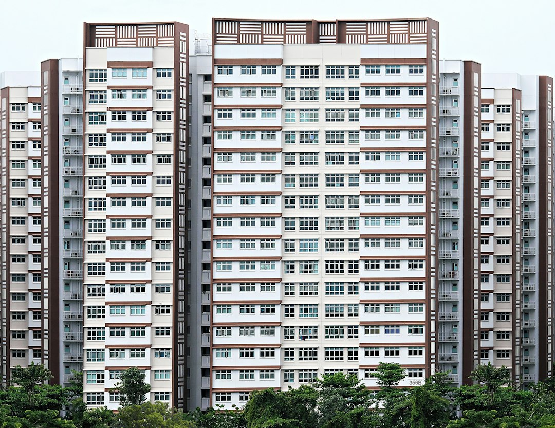 a tall white and brown building with trees in front of it