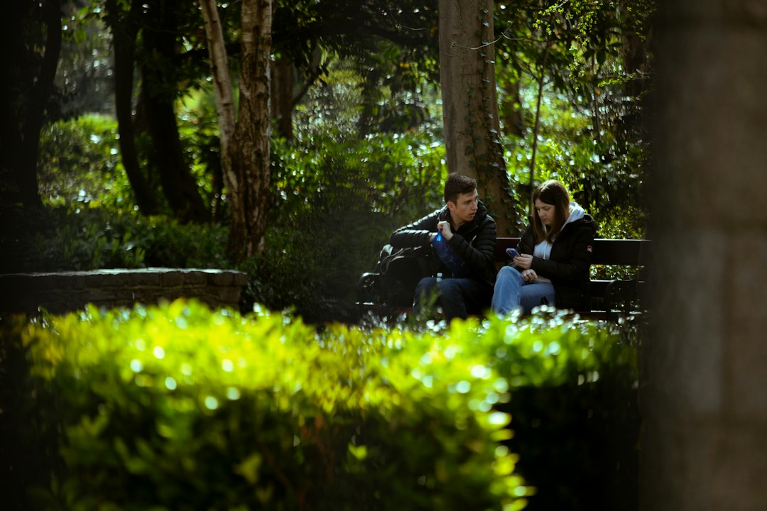 Couple sitting on a park bench surrounded by trees
