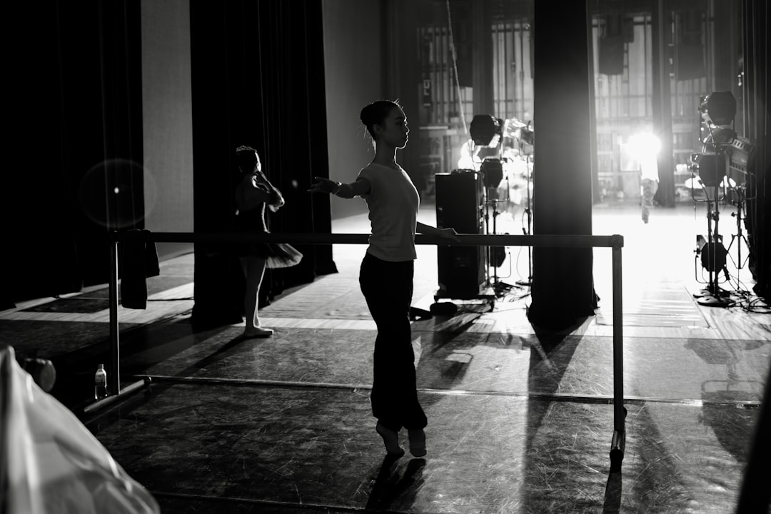 Ballerinas practice at a barre in a theater.