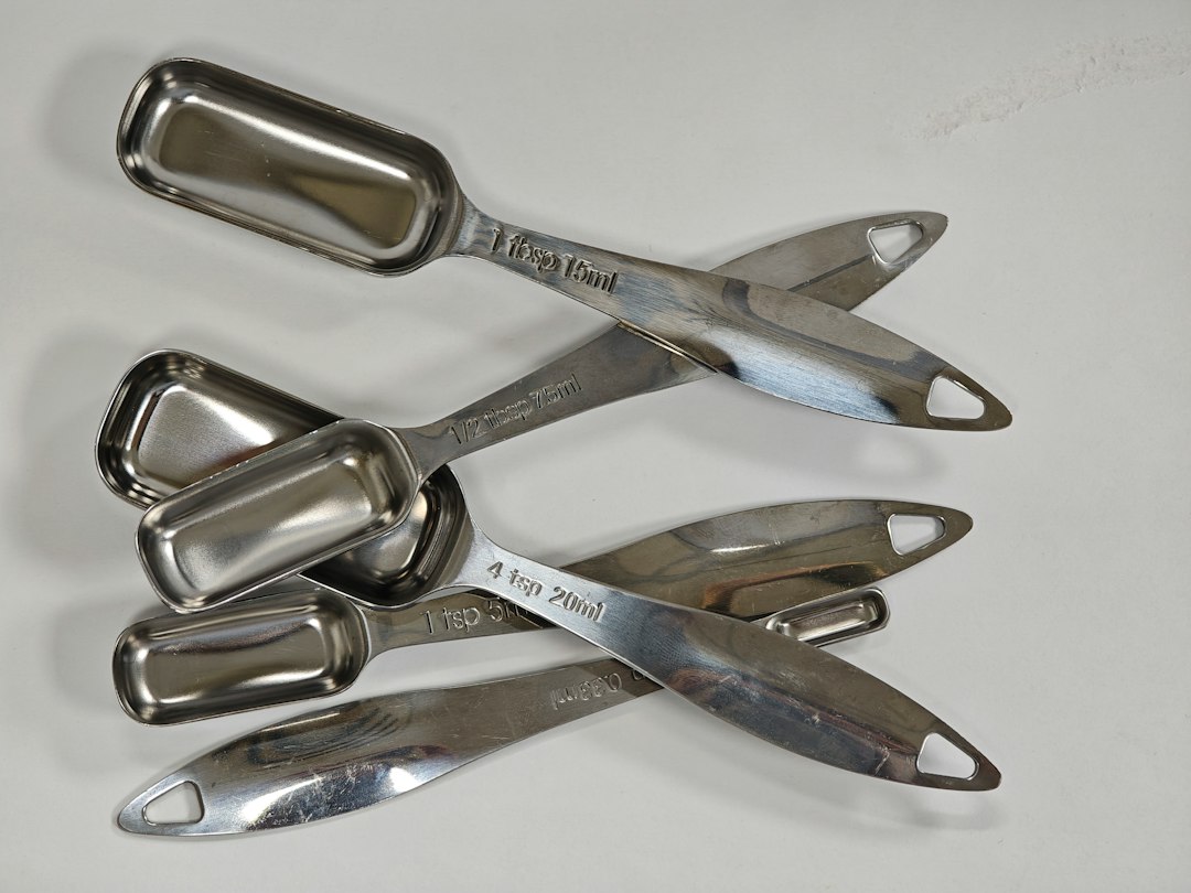 Stainless steel rectangular measuring spoons on a white surface