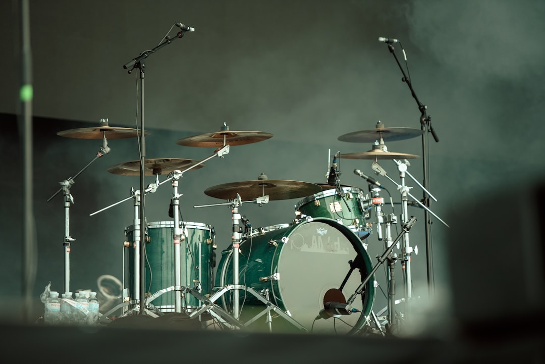 A green drum set with microphones on stage