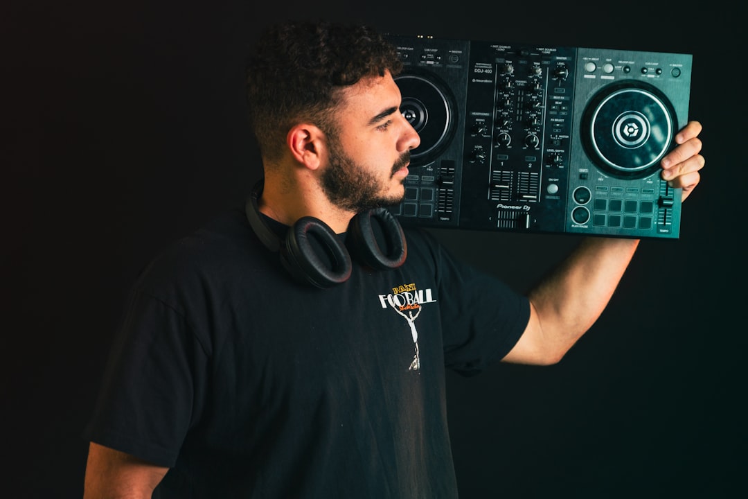 Man holding dj controller with headphones around neck