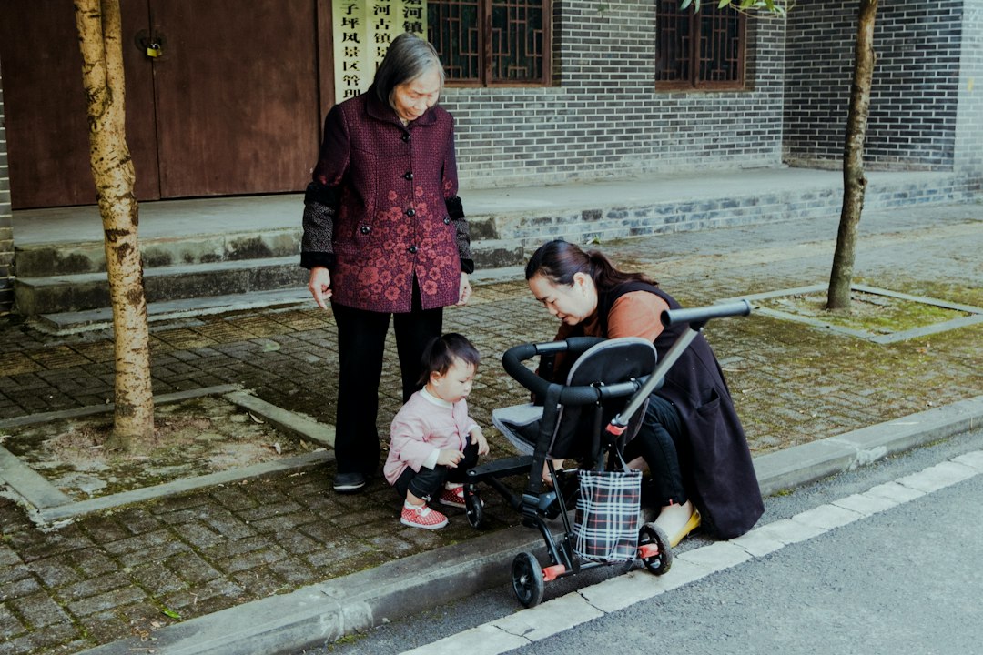 woman in pink and black coat holding black stroller