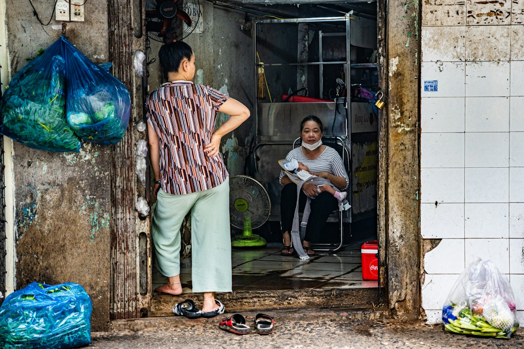 Two women in a doorway with bags and without masks