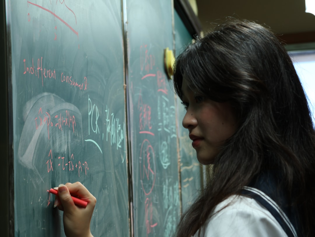 A student writes on a blackboard in a classroom.