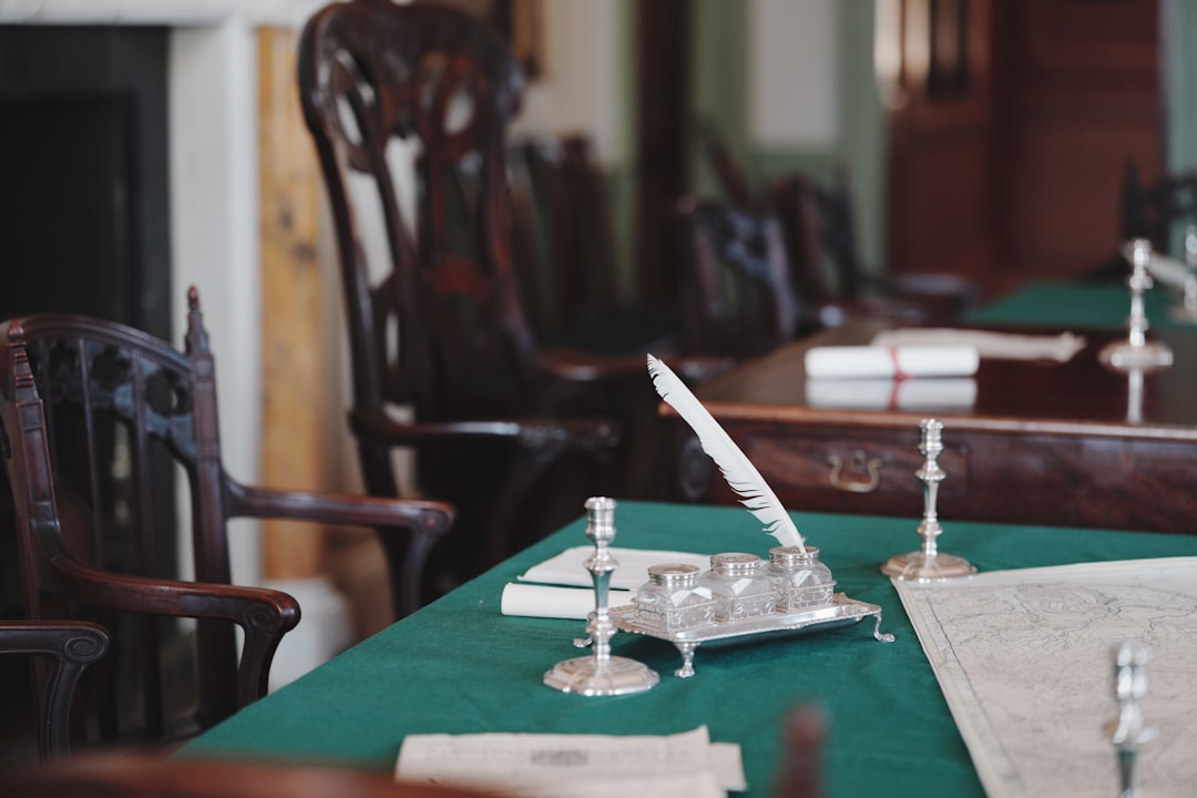A quill pen and inkwell on a green desk