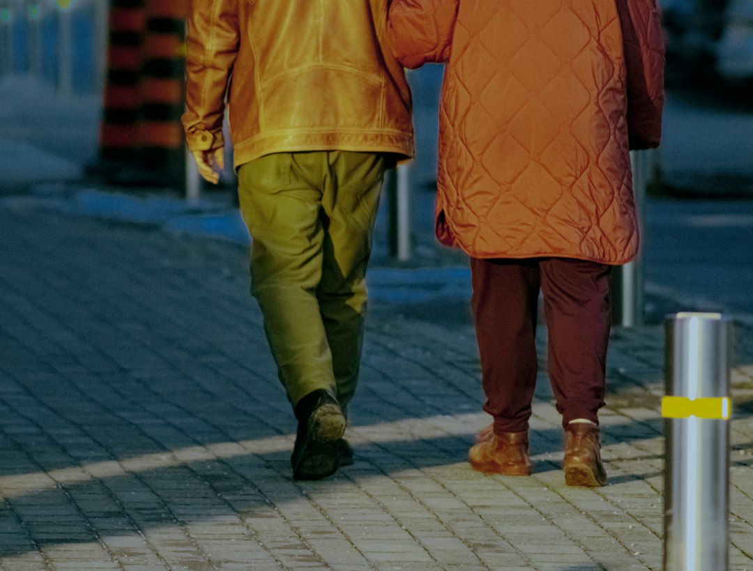 Two people walking arm in arm on a sidewalk