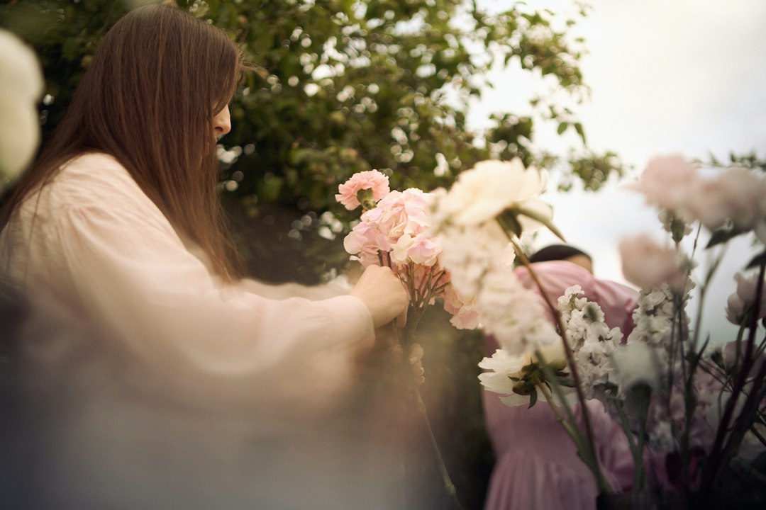 Young woman arranging pink flowers in a lush garden