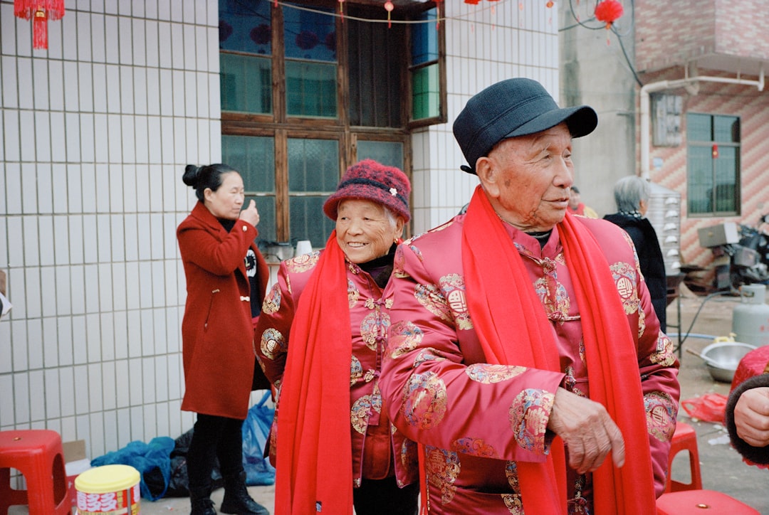 Elderly couple in traditional red attire smiling outdoors