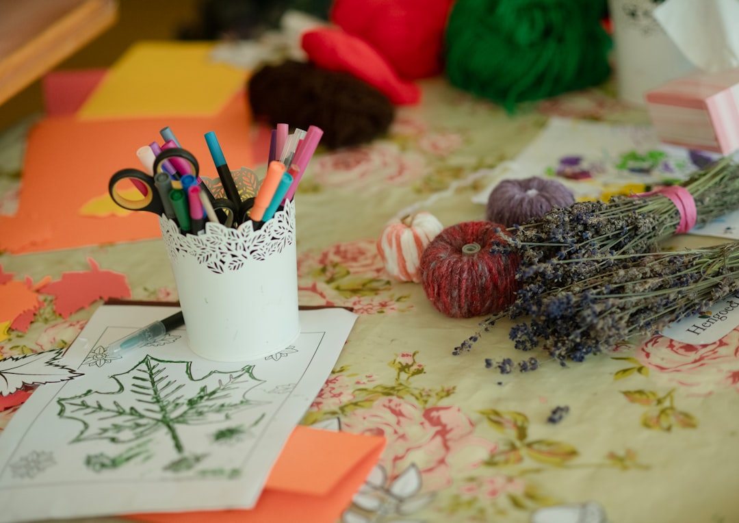 Art supplies and dried lavender on a floral tablecloth.
