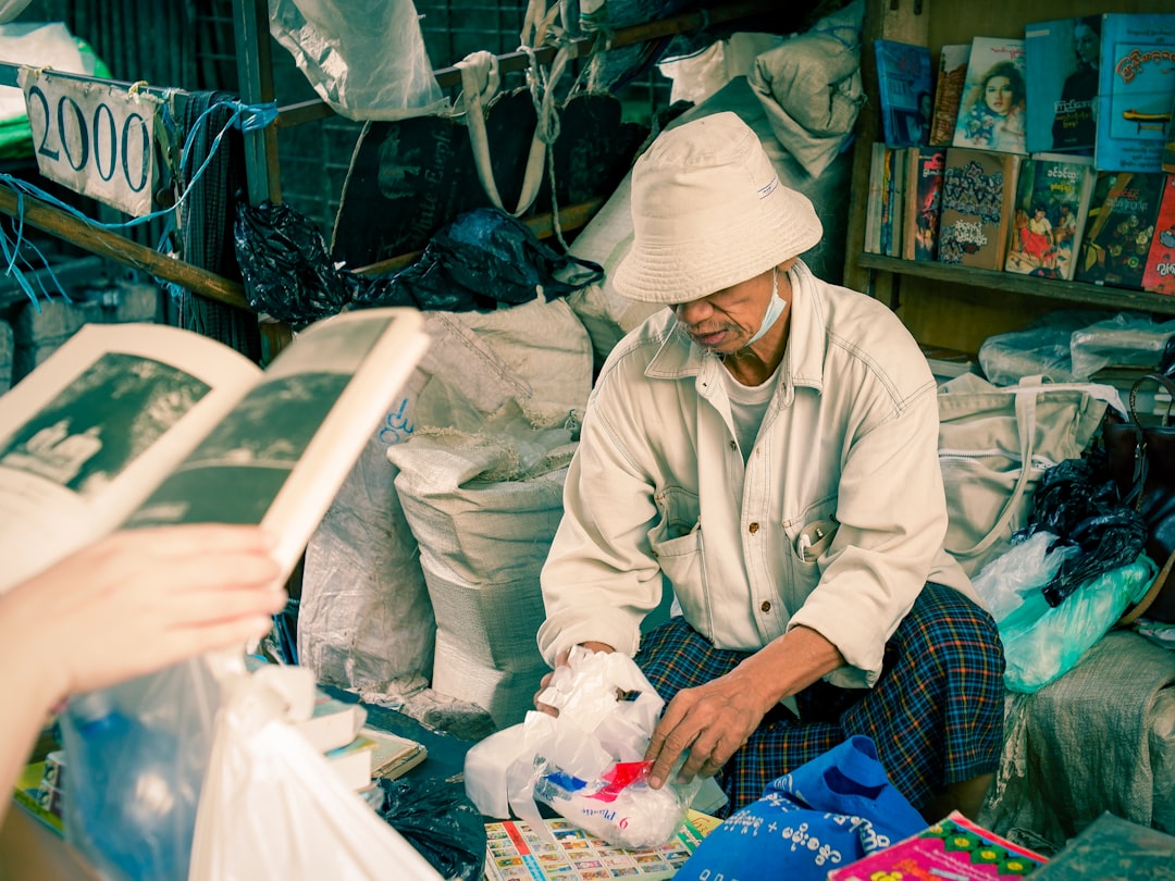 Elderly man in a market surrounded by goods