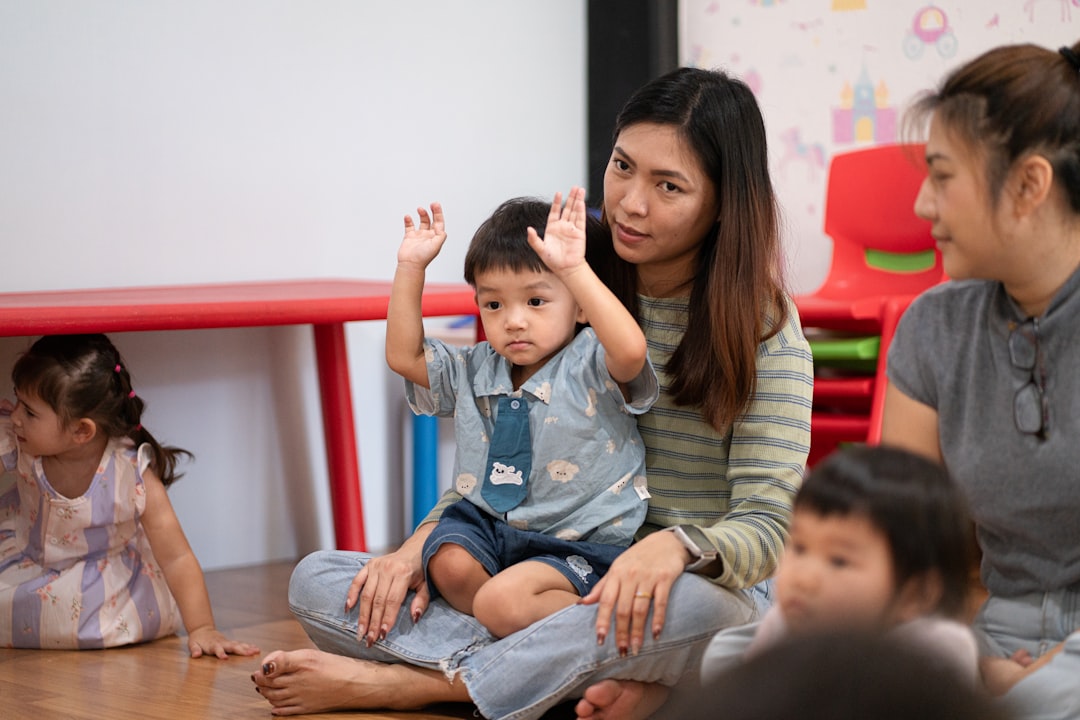 A woman holding a child with raised hands in a classroom setting