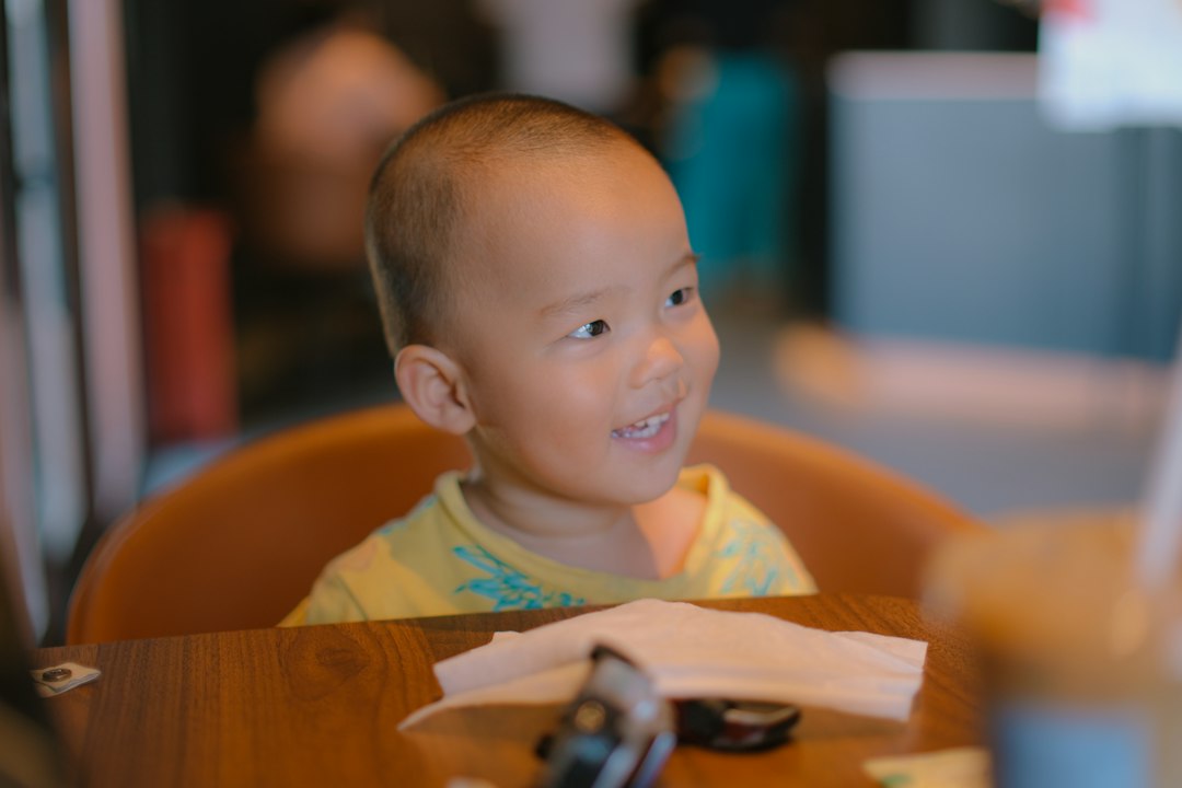 A little boy sitting at a table with a cell phone