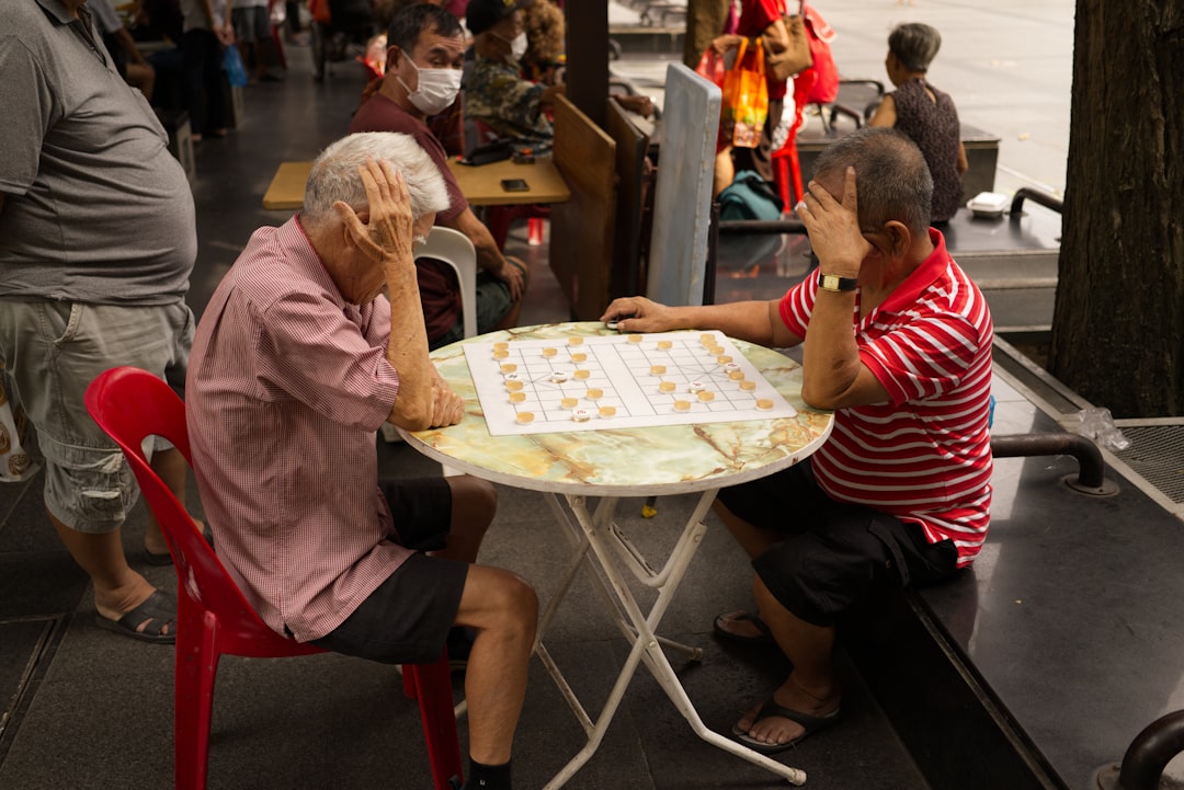 Two elderly men playing a board game at a table.