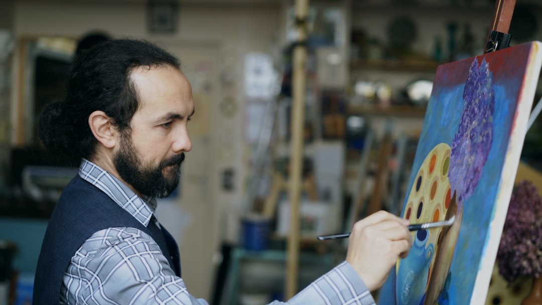 Artist painting a colorful abstract canvas in studio