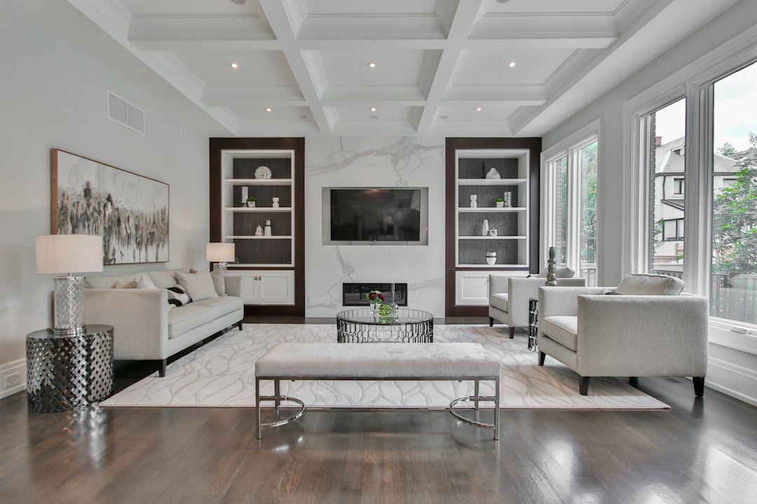 A living room with a marble fireplace, white sofas, and dark wood shelving