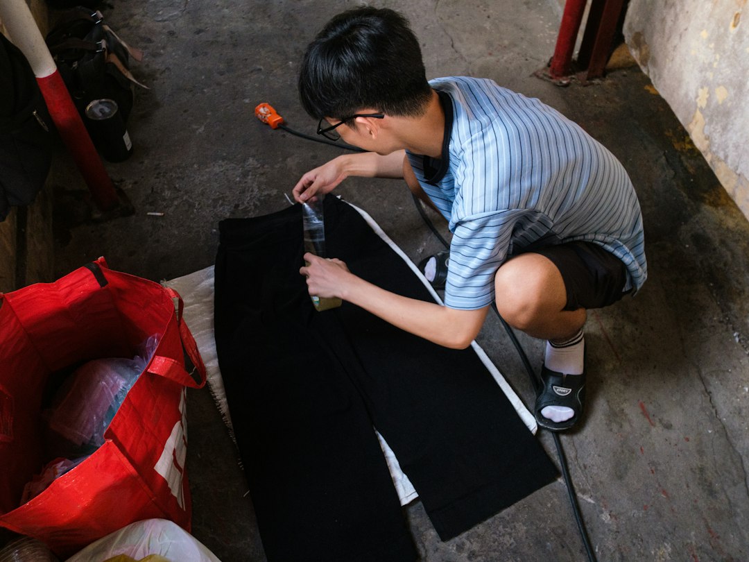 Young man applying liquid to black pants on floor