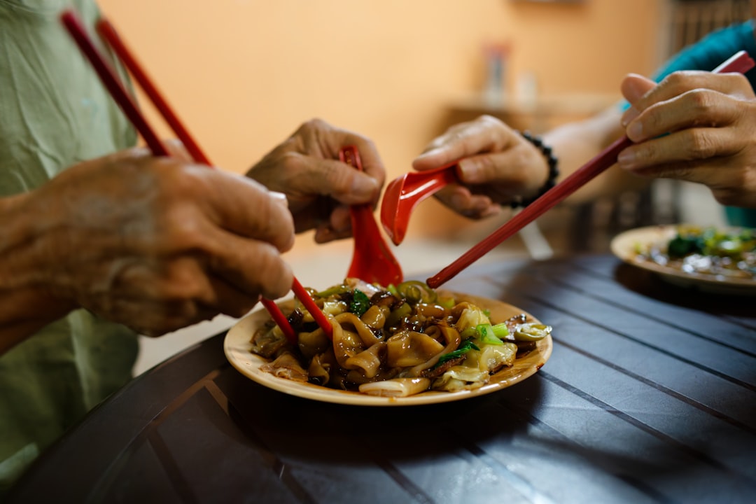 People eating a meal with chopsticks and a spoon.