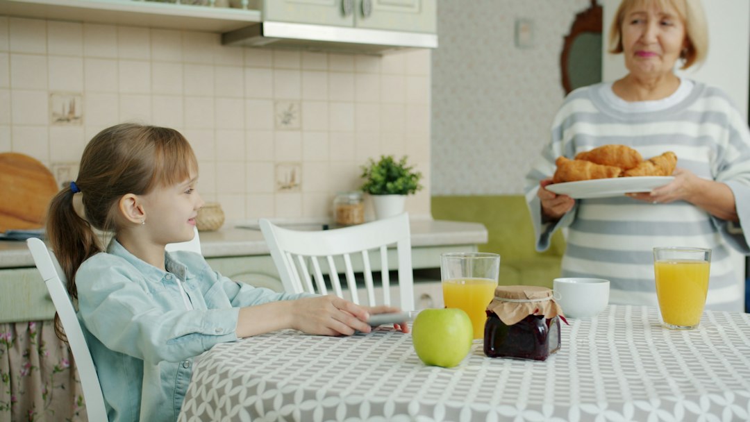 Grandmother serves croissants to girl at kitchen table