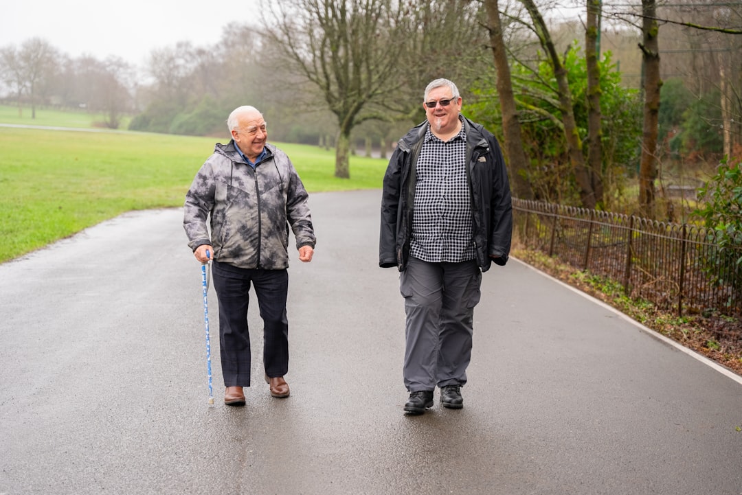 Two older men walking down a paved road