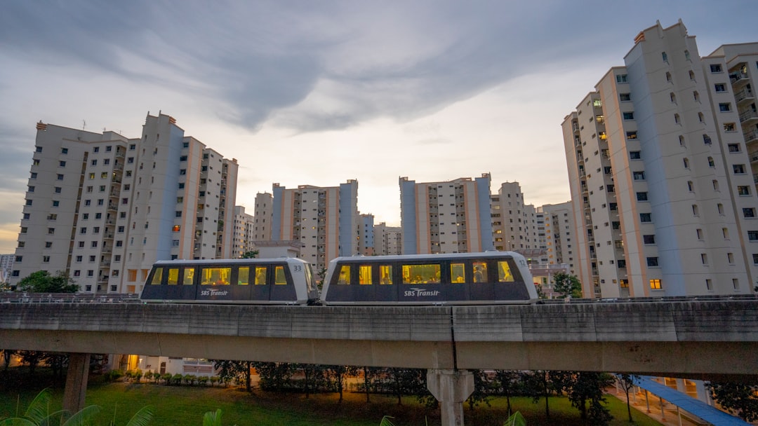 blue and white train on rail near city buildings during daytime