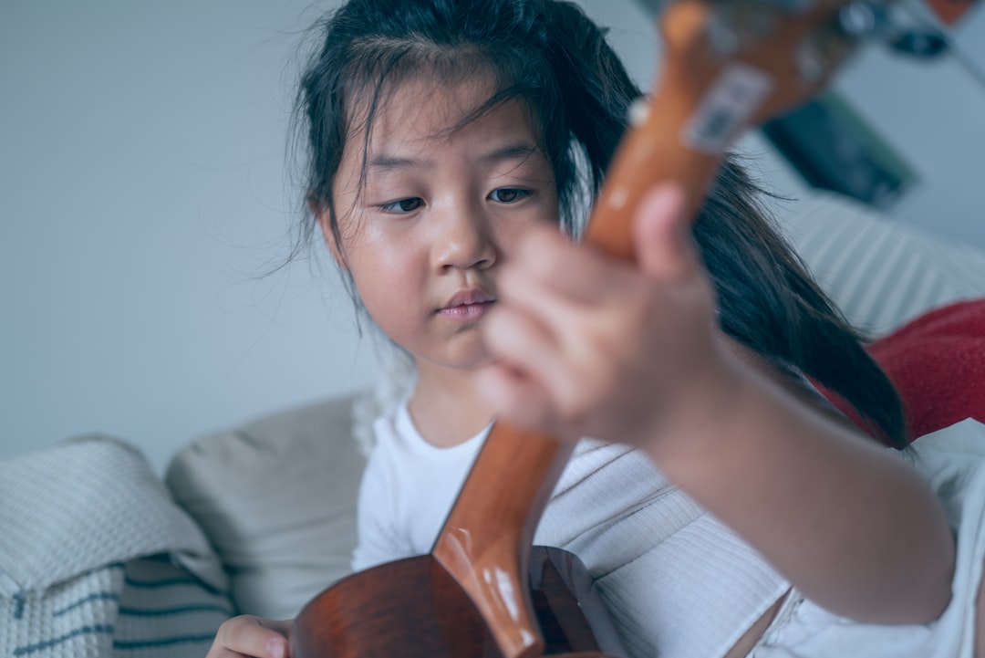 Young girl plays the ukulele intently